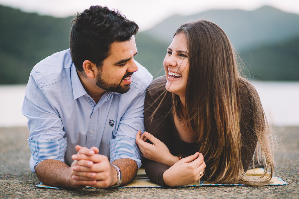 Casal deitado no chão se olhando e gargalhando