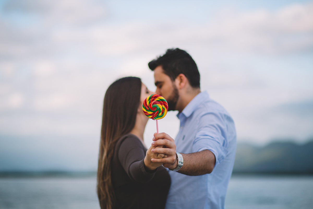 Pirulito colorido segurado pelo casal que esta se beijando