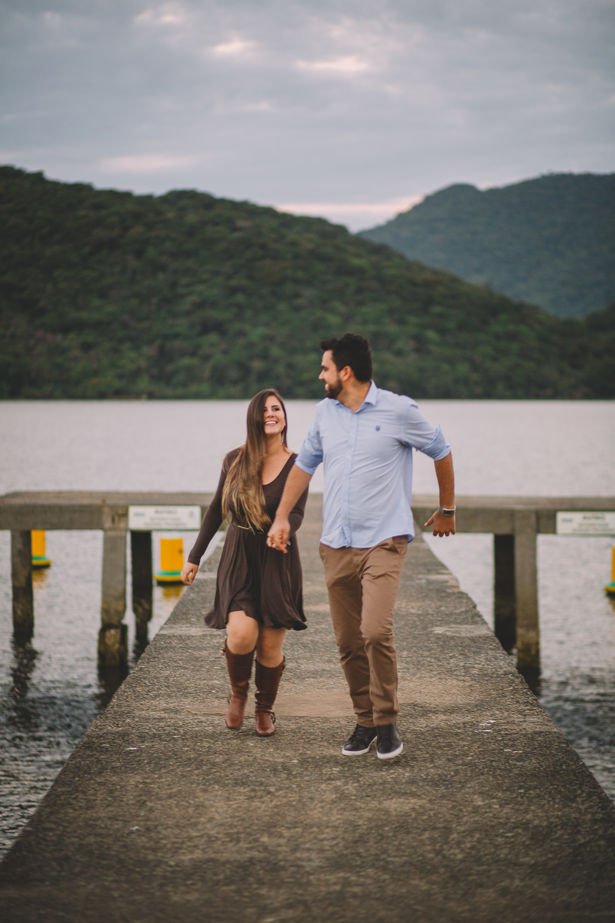 Fim do ensaio de pré casamento com os noivos correndo de mãos dadas em direção ao fotógrafo