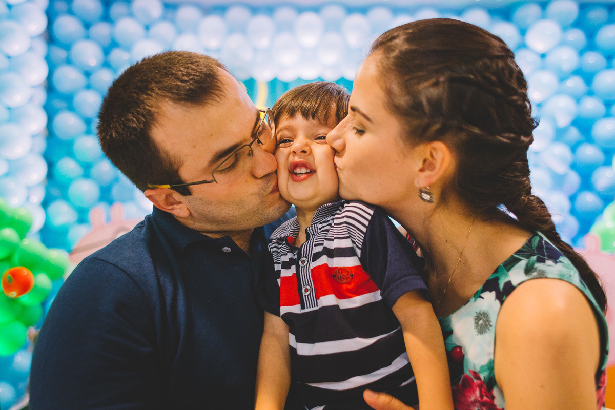 Pais beijando a criança que esta de aniversário
