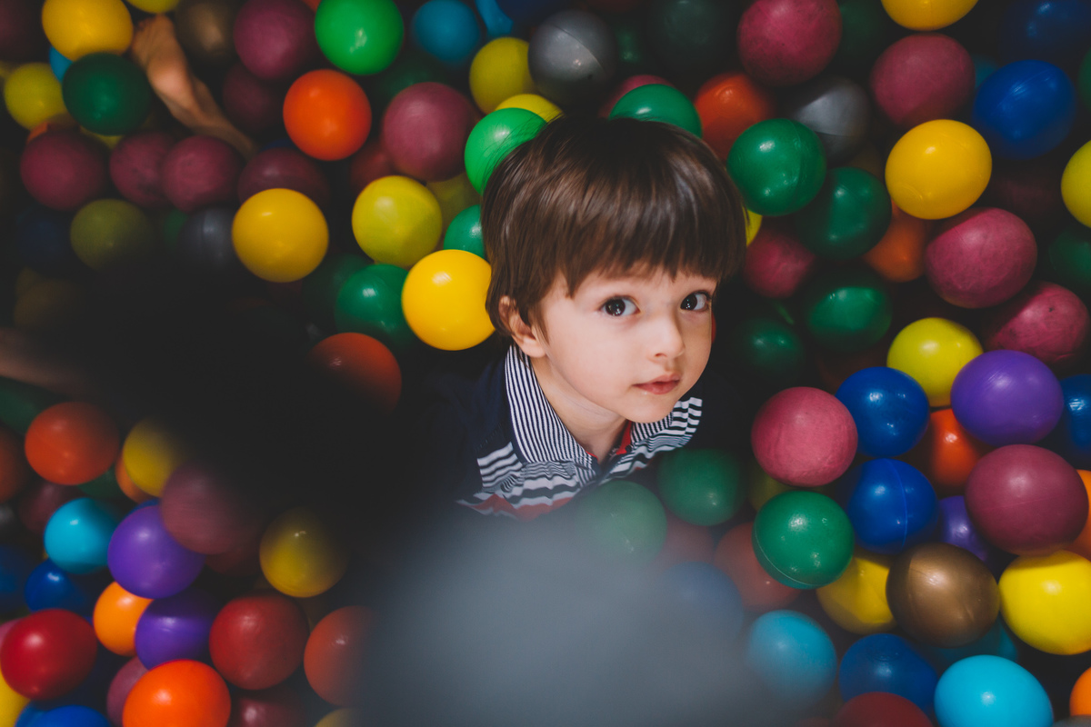 Criança dentro da piscina de bolinhas olhando para câmera