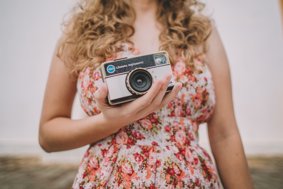 Moça segurando uma câmera de filme antigo