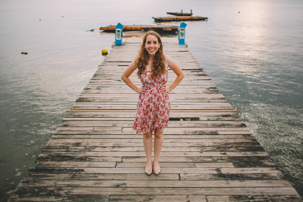 Mulher sorrindo em cima de um deck de madeira da beira do mar