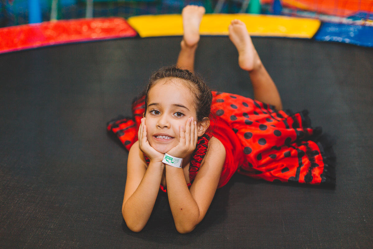Criança deitada na cama elástica com as mãos no queixo