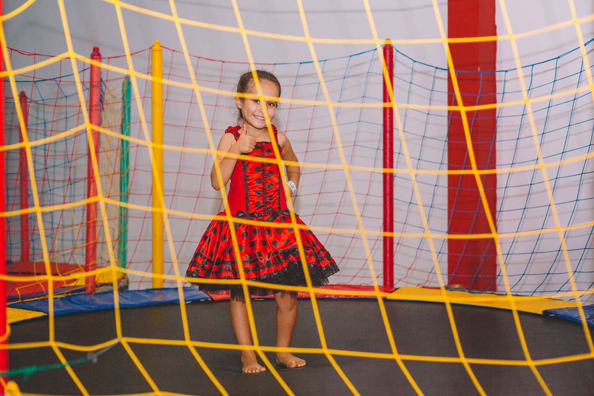 Menina sorrindo para a câmera na cama elástica
