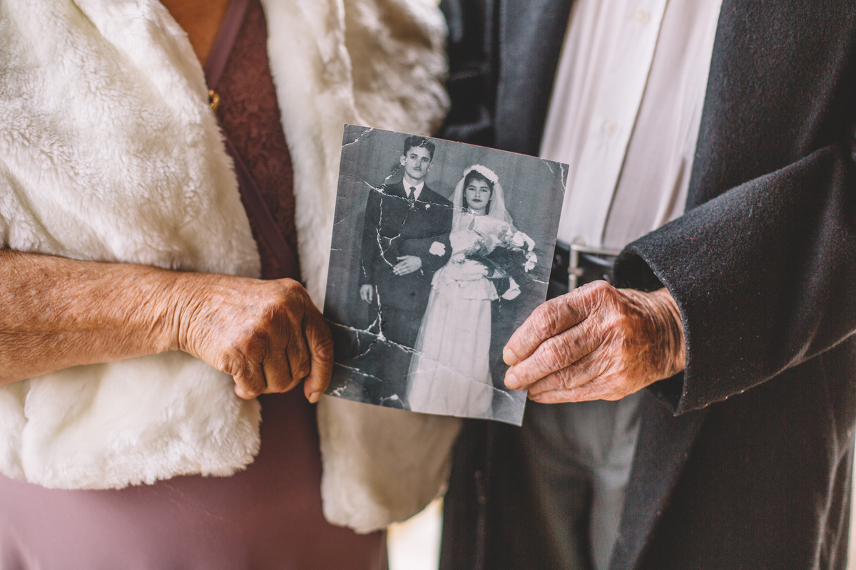 Casal de avós segurando a foto antiga do casamento