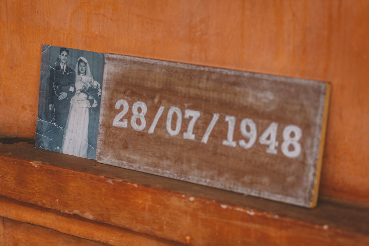 Foto do casamento do lado de uma placa de madeira com a data do casamento 