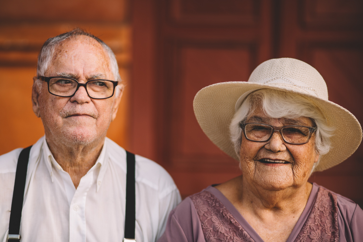 Senhor olhando desconfiado e Senhora sorrindo para a câmera