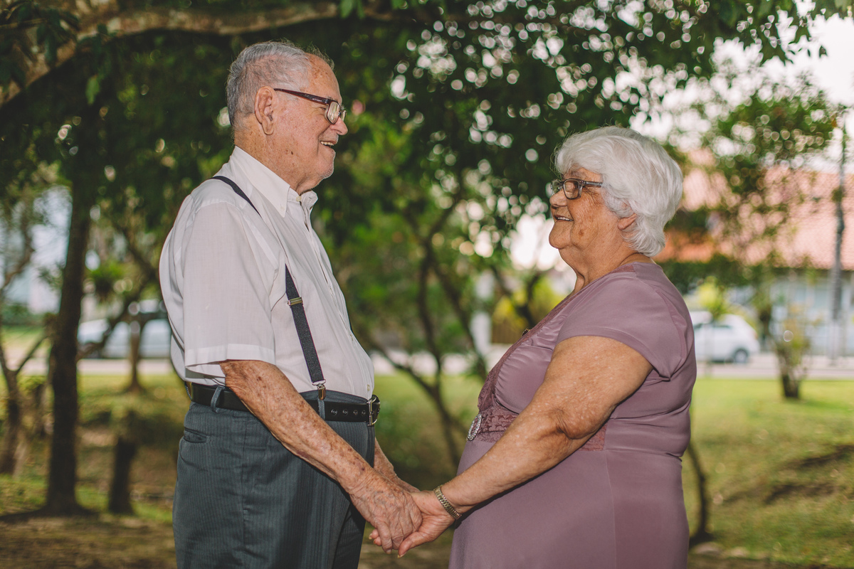 Velhinhos de mãos dadas sorrindo um para o outro