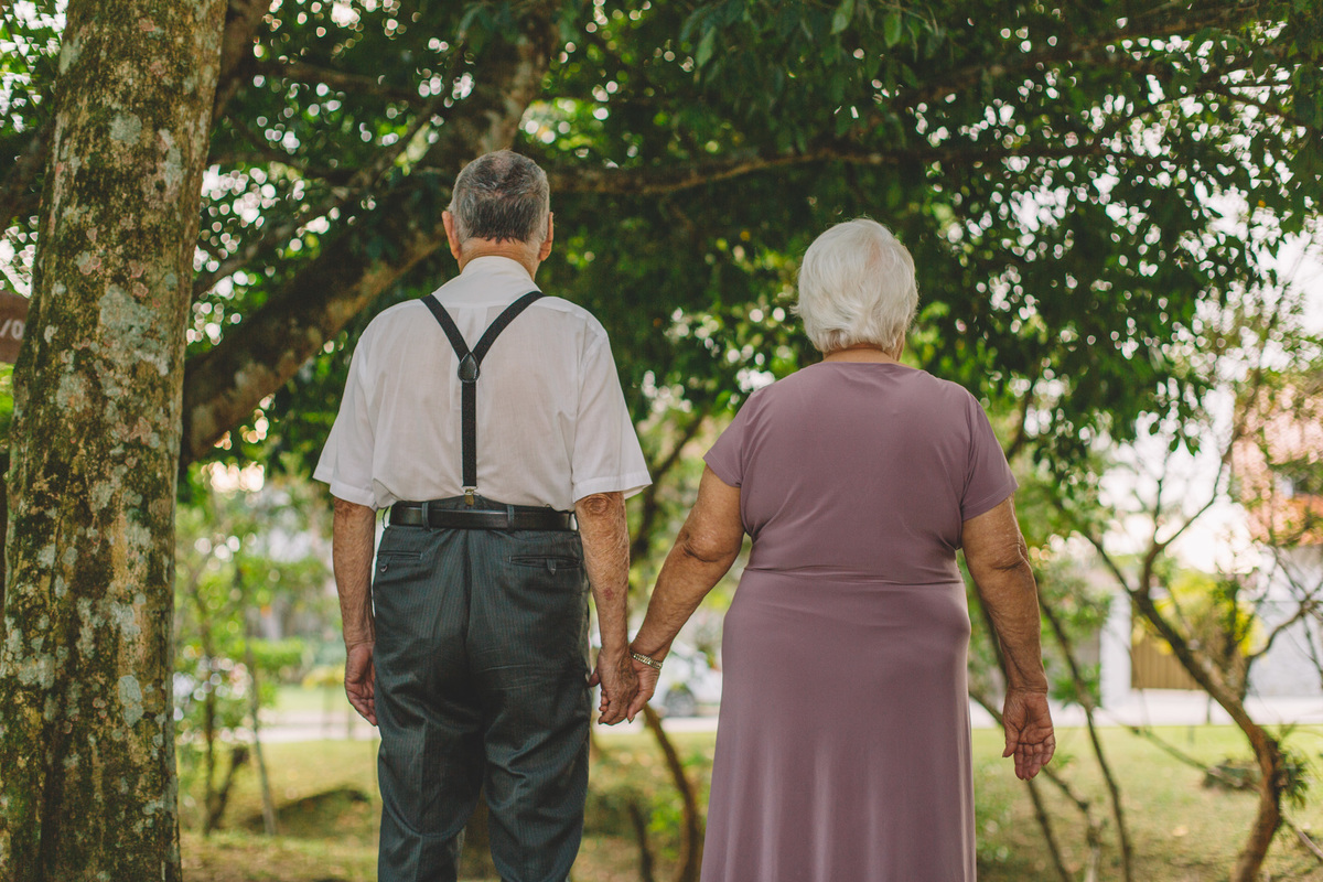 casal de idosos de costas andando de mãos dadas