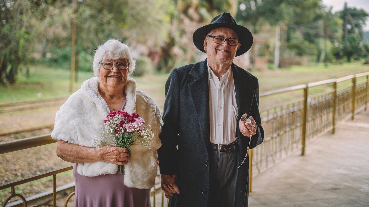 Casal de velhinhos de mãos dadas sorrindo 