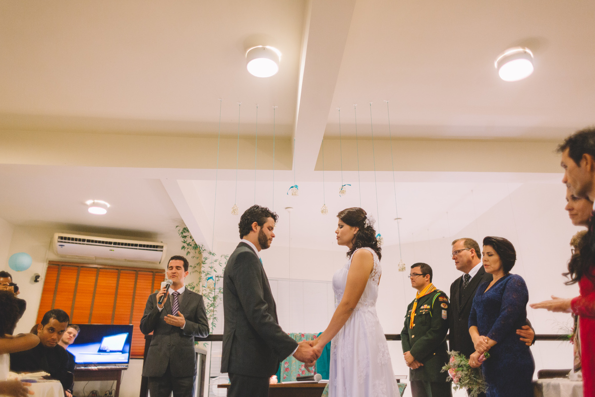 Noivos de mãos dadas enquanto um convidado canta uma música