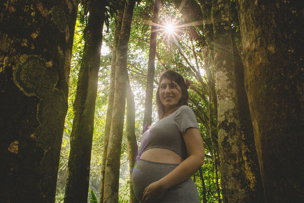 Mulher grávida entre as árvores