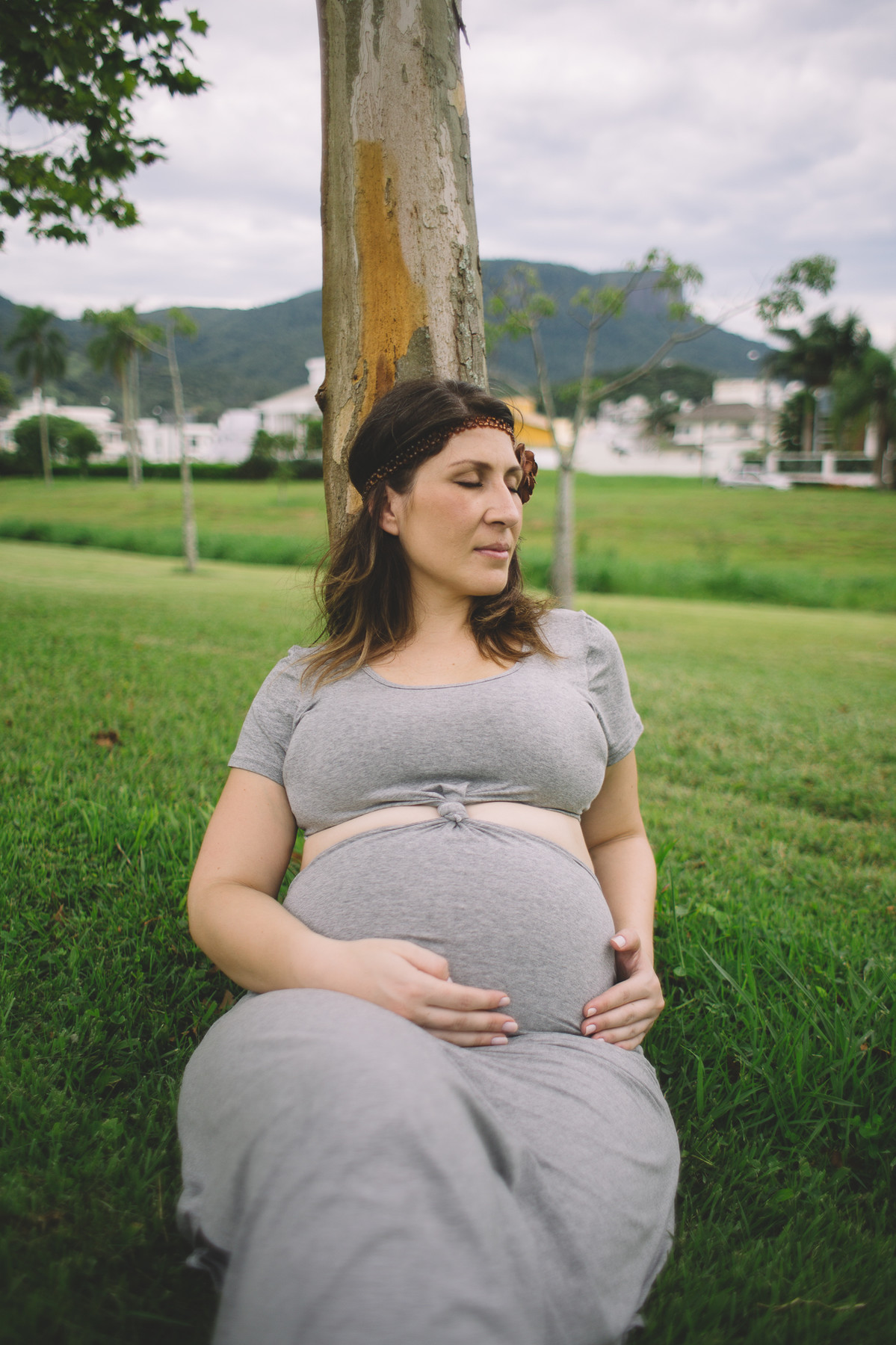 Grávida relaxando encostada numa árvore