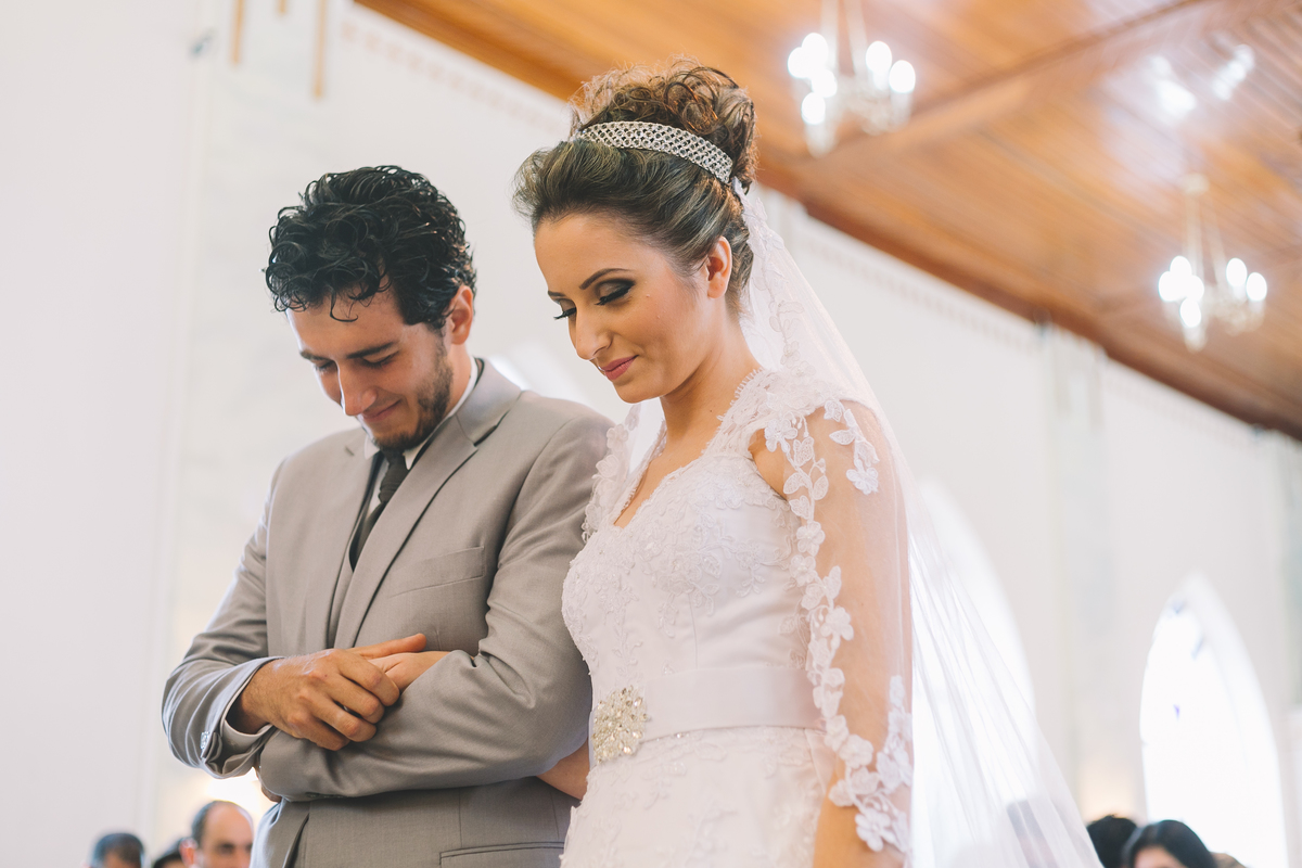 Noivos de braços dados com os olhos fechados na oração