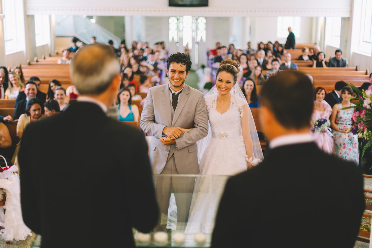 Noivos felizes focados e os convidados na igreja desfocados