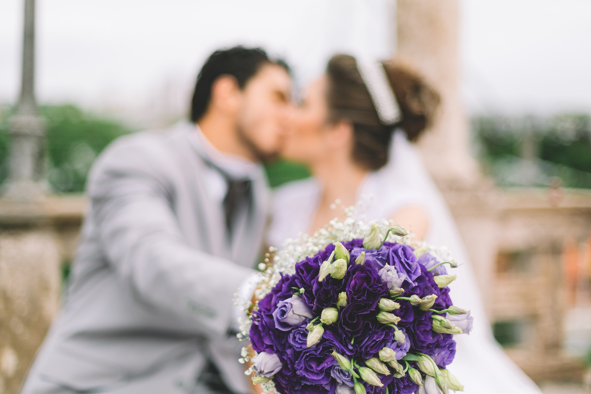 casados se beijando e o foco no buquê da noiva