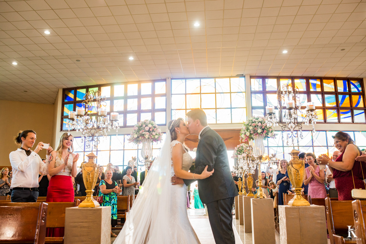 cerimonia de casamento em quedas do iguaçu, noivo de terno e noiva com vestido branco e buquet na igreja matriz saida dos noivos com o beijo e chuva de arroz fotografo katy tesser