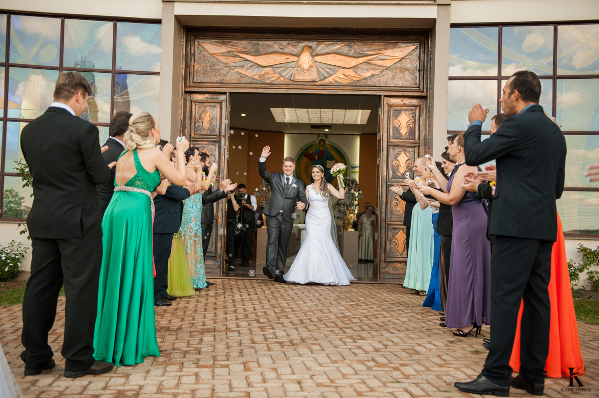 cerimonia de casamento em quedas do iguaçu, noivo de terno e noiva com vestido branco e buquet na igreja matriz saida dos noivos com o beijo e chuva de arroz fotografo katy tesser