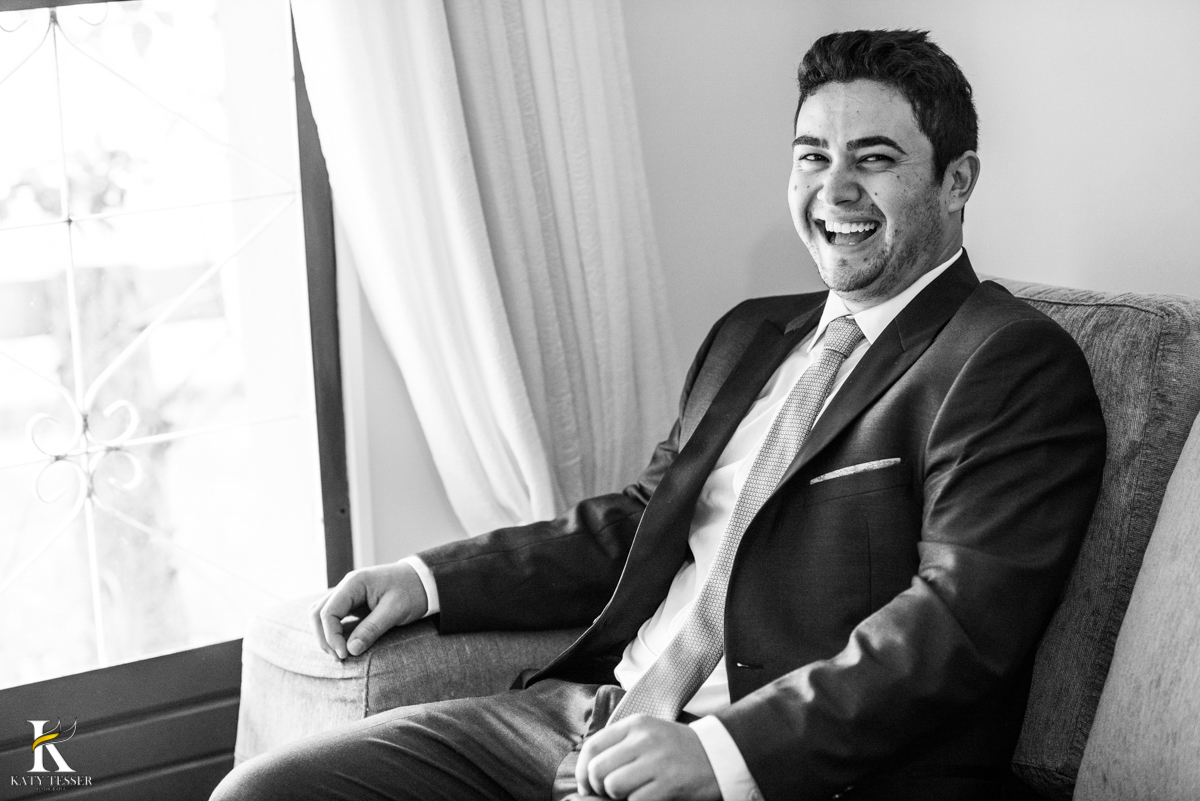 making of do noivo vestido com o terno, sentado em casa fotografo katy tesser