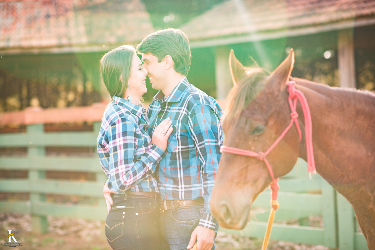 sessão pre casamento, na fazenda com cavalos e outros animais, com um casal com roupas cowntry a noiva com vestido branco, registrado pela fotografa katy tesser