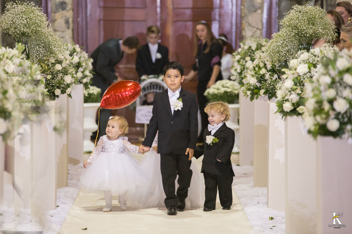 cerimonia religiosa de camila e fernando no santuario de nossa senha aparecida em laranjeiras do sul a decoração rosas brancas pajens com carrinho de bebe plaquinhas com mensagens e uma boneca com as alianças katy tesser fotografo