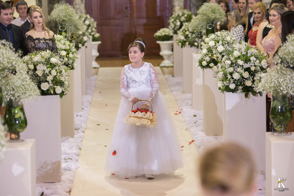 cerimonia religiosa de camila e fernando no santuario de nossa senha aparecida em laranjeiras do sul a decoração rosas brancas pajens com carrinho de bebe plaquinhas com mensagens e uma boneca com as alianças katy tesser fotografo