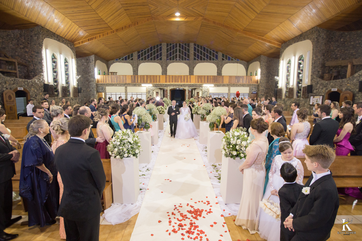 cerimonia religiosa de camila e fernando no santuario de nossa senha aparecida em laranjeiras do sul a decoração rosas brancas pajens com carrinho de bebe plaquinhas com mensagens e uma boneca com as alianças katy tesser fotografo