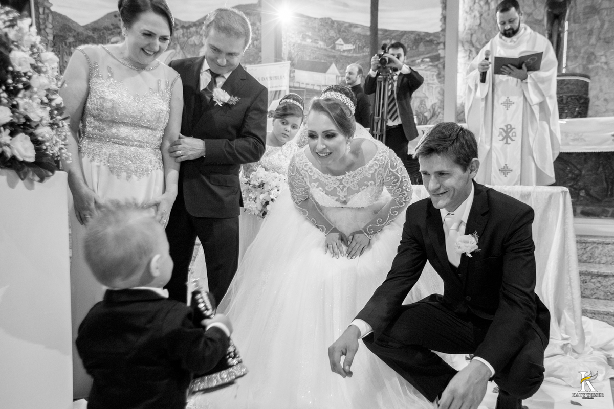 cerimonia religiosa de camila e fernando no santuario de nossa senha aparecida em laranjeiras do sul a decoração rosas brancas pajens com carrinho de bebe plaquinhas com mensagens e uma boneca com as alianças katy tesser fotografo