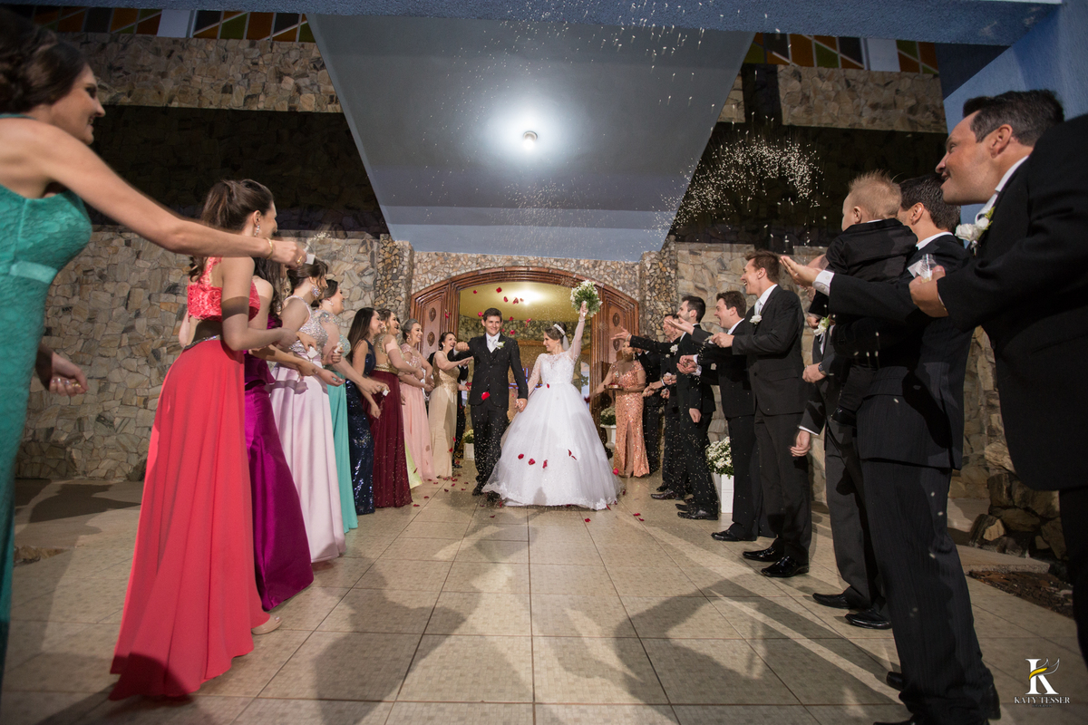 cerimonia religiosa de camila e fernando no santuario de nossa senha aparecida em laranjeiras do sul a decoração rosas brancas pajens com carrinho de bebe plaquinhas com mensagens e uma boneca com as alianças katy tesser fotografo chuva de arroz