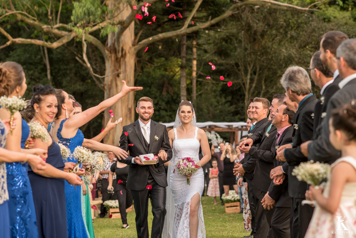 Casamento ao ar livre de dia na cabana manhare em Francisco beltrao parana de Ademir ana Paula as fotos de katy tesser fotografo na saida dos noivos com corredor de padrinhos e petalas de rosa