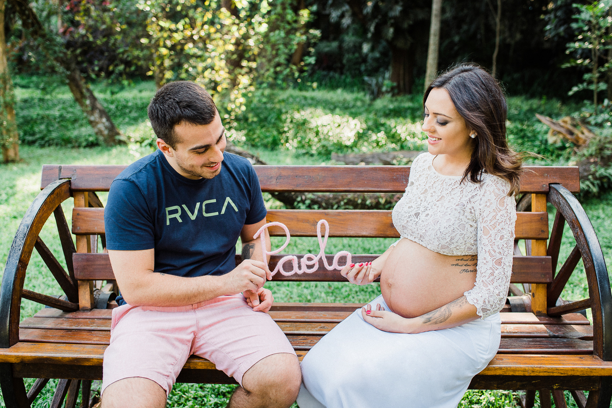 Ensaio gestante parque Burle Marx Casal feliz sentado banco de madeira segurando nome