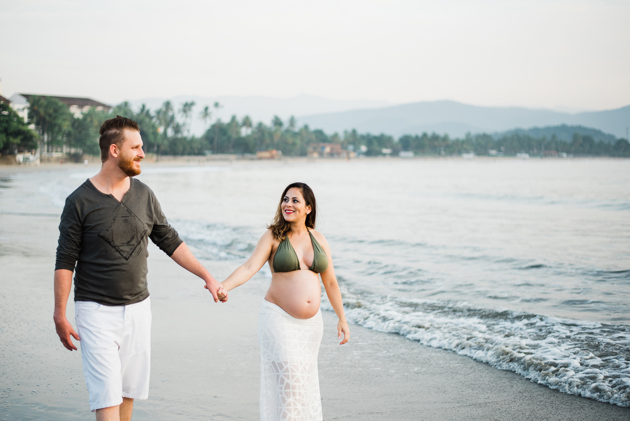 Ensaio gestante praia do Guarujá casal feliz de mãos dadas