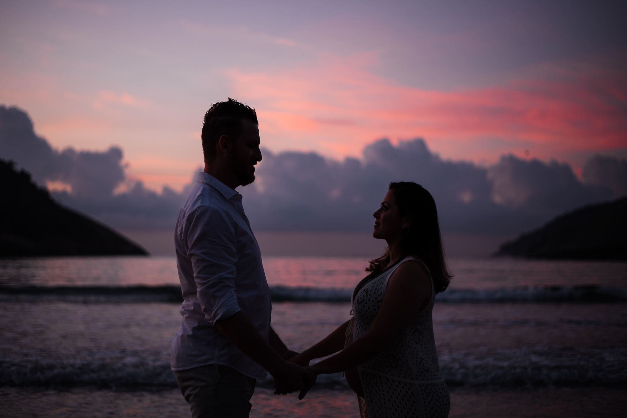 Ensaio gestante praia do Guarujá casal de mãos dadas silhueta