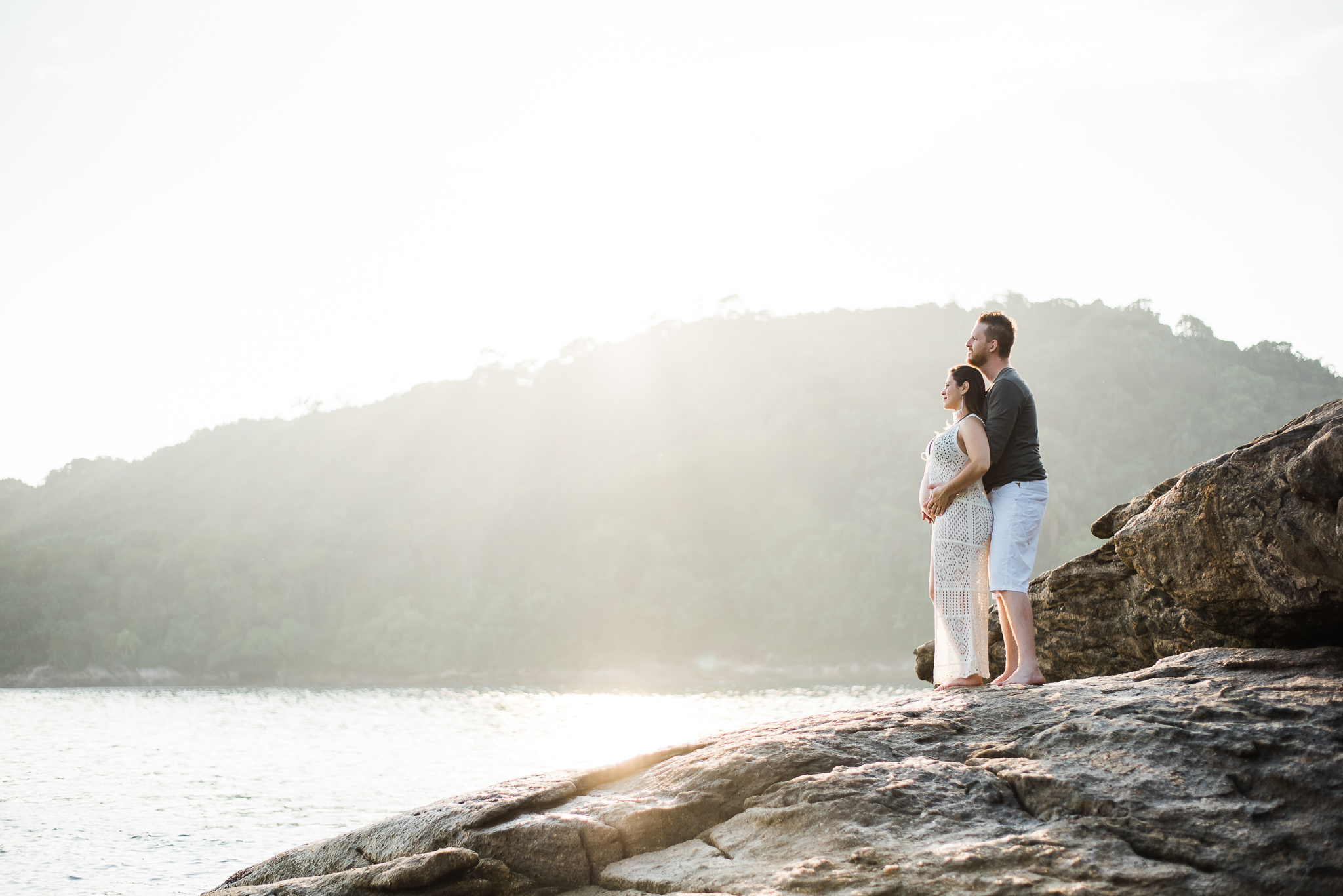 Ensaio gestante praia do Guarujá casal feliz abraçados