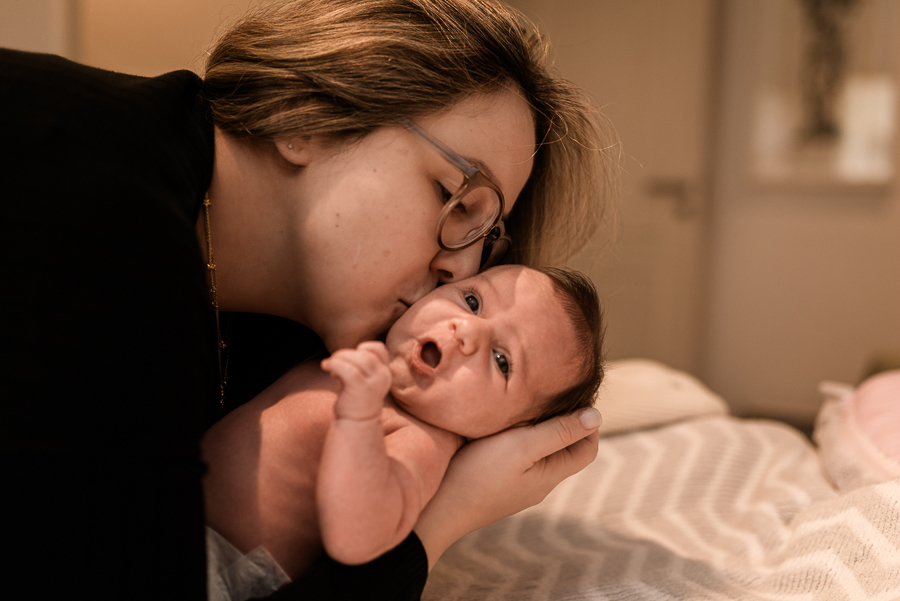 mãe beijando bebê recém nascido em ensaio fotográfico documental
