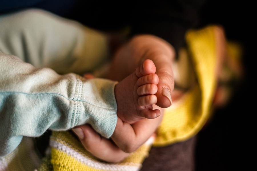 mão da mãe segurando o pé do bebê em ensaio fotográfico em casa