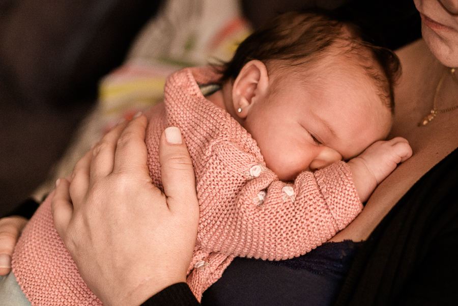 detalhe de bebê dormindo no colo ca mãe