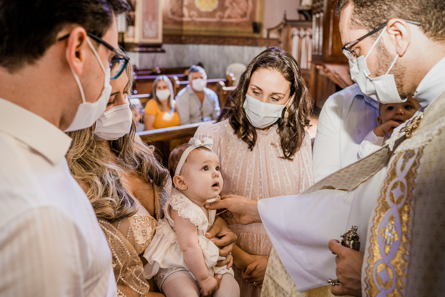 fotografia de batizado: o padre ungindo a bebê