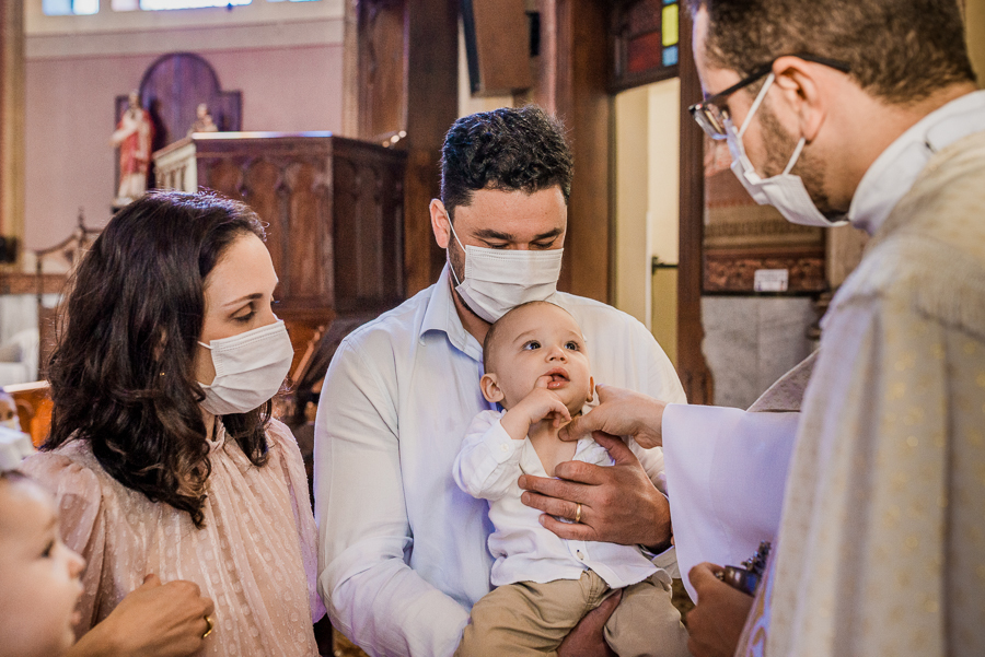fotografia de batizado: o padre ungindo o bebê