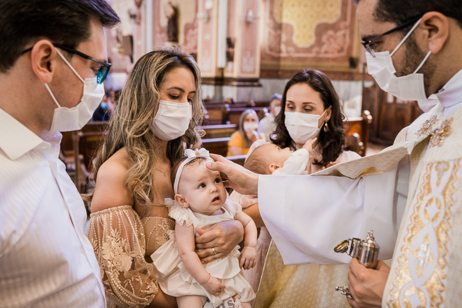 fotografia de batizado: o padre ungindo a bebê