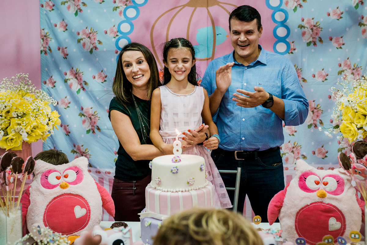 criança com pais atrás do bolo