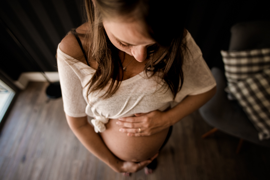 Foto da gestante, tirada do alto. Ensaio feito na casa da cliente.