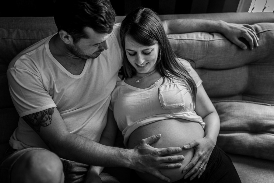 Casal no sofá de casa. Mulher gestante.