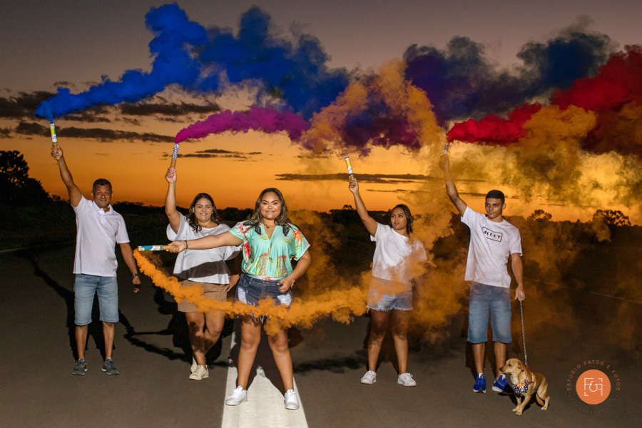 debutante soltando fumaça colorida com a família pais e irmãos