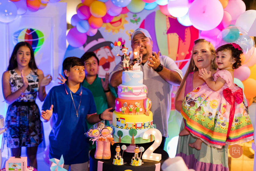 aniversariante menina cantando parabéns com os pais e irmãos