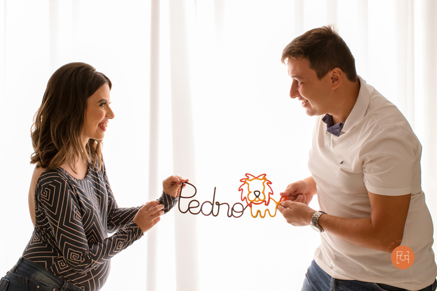 mamãe gestante com o papai segurando o nome do bebê em arte de arame