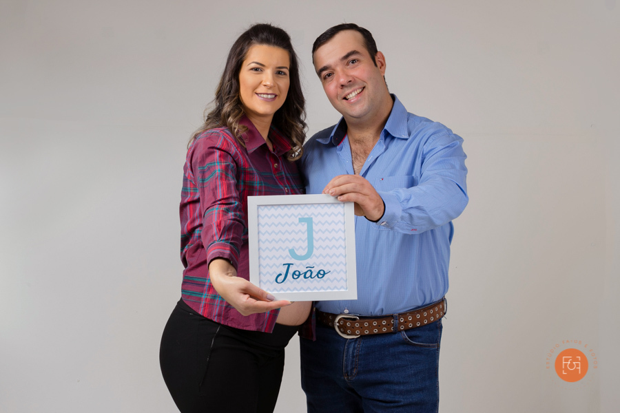 gestante abraçada com o papai segurando a placa da maternidade