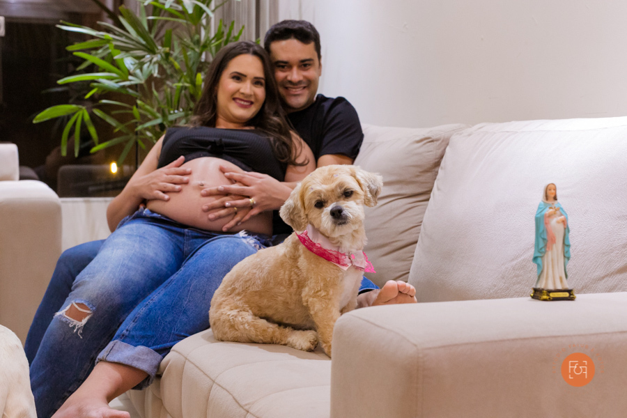 gestante com o papai sentados no sofá com os pets e nossa senhora