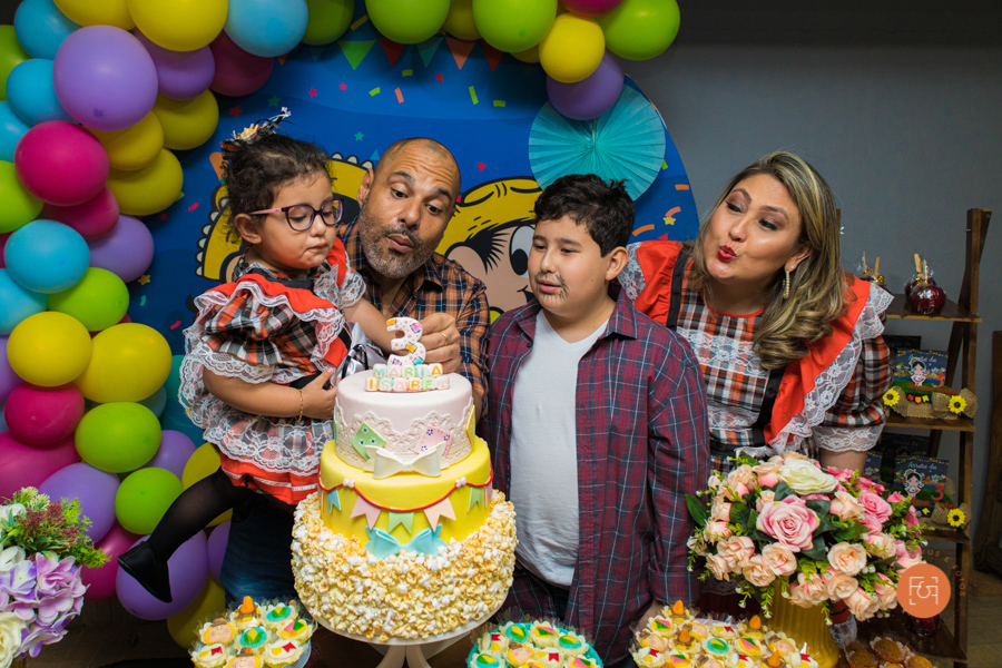 aniversariante menina cantando parabéns com os pais e o irmão